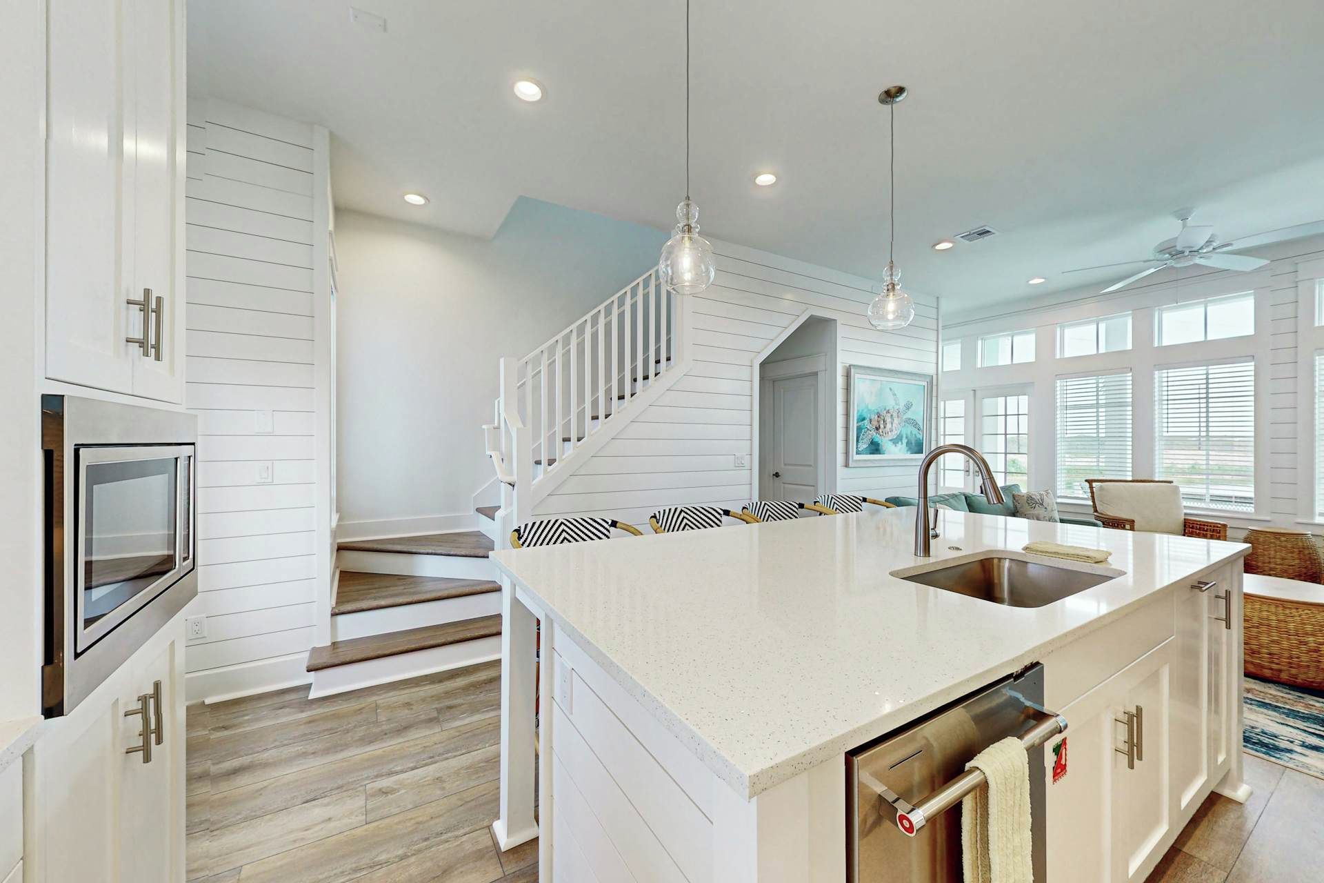 A modern kitchen with a central island, stainless steel appliances, and a staircase leading to an upper level.