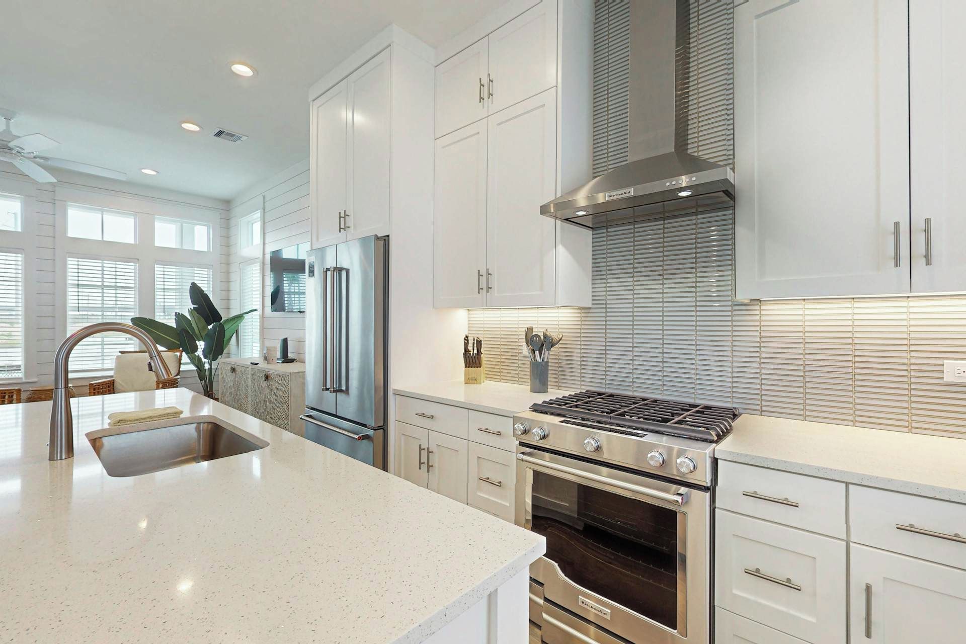 A modern kitchen with stainless steel appliances, white cabinetry, and a large island with a sink.