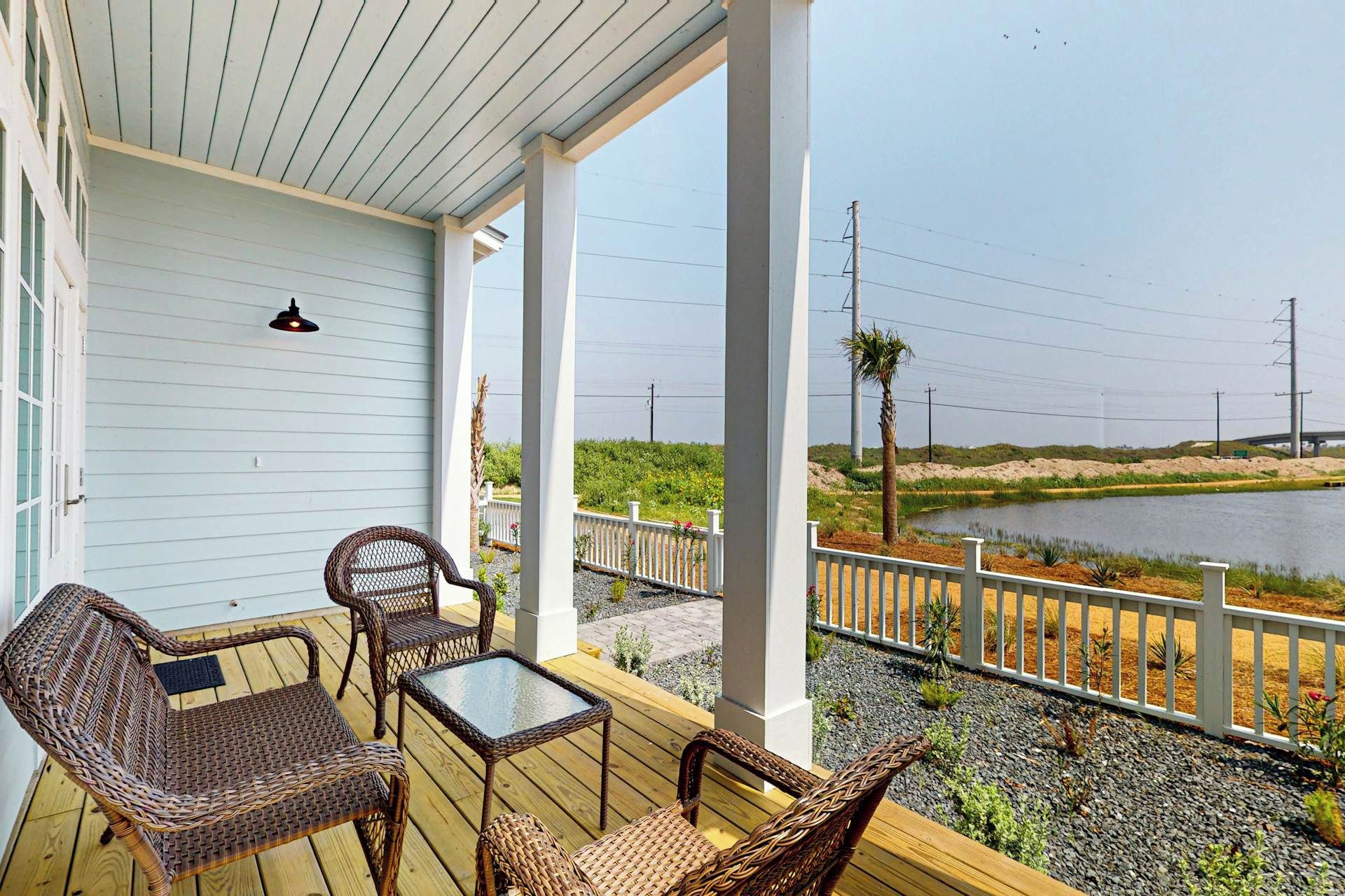 A covered outdoor area with wicker furniture and a view of a lake.