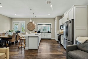 A spacious kitchen with a central island, white cabinetry, and stainless steel appliances. - Sea Gem | Golf Views | Steps to Beach (Port Aransas)