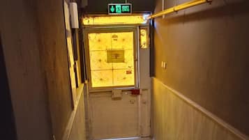 Un pasillo con piso de madera, una puerta con un letrero y una lámpara en el techo.