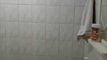 Un baño con un lavamanos blanco, un espejo, una toalla colgada en la pared y una botella de jabón.