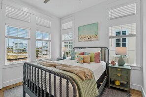 A bedroom with a bed, bedside tables, and a view of the outside. - Siren Song | Steps to Beach | Resort Amenities (Port Aransas)