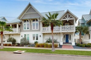 A two-story house with a balcony, a front door, and a small porch area. - Sleek Beach | Steps to Beach | Resort Amenities (Port Aransas)