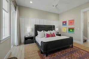 Ein Schlafzimmer mit Bett, Nachttischen, Deckenventilator und Kunstwerken an der Wand.