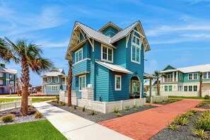 A two-story residential building with a gabled roof and a front porch. - Sun-Drenched On Sundew | Steps to Beach | Resort (Port Aransas)