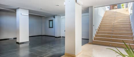 A spacious interior with a staircase leading to an upper level, a potted plant, and a door at the end of the hallway.