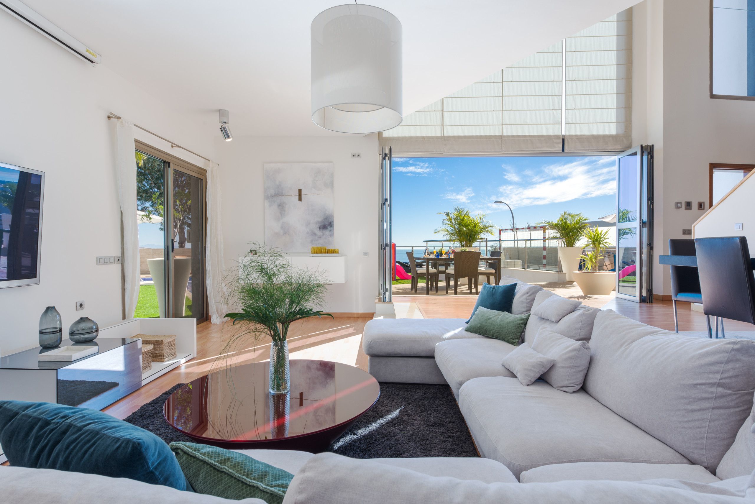 A modern living room with a sofa, coffee table, and a view of the outdoor terrace.