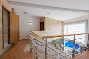 A modern interior with a wooden staircase, a view of a pool, and a high ceiling. - Villa Sunset Haven Adeje (Adeje)
