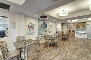 A spacious dining area with high ceilings, modern lighting fixtures, and artwork on the walls. - Sunrise Villa | Steps to Beach | Resort Amenities (Port Aransas)