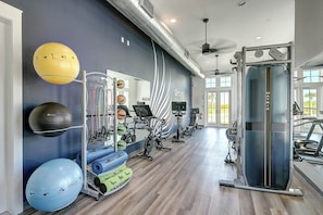 A gym with exercise equipment, a large mirror, and a view of the outdoors. - Sunrise Villa | Steps to Beach | Resort Amenities (Port Aransas)