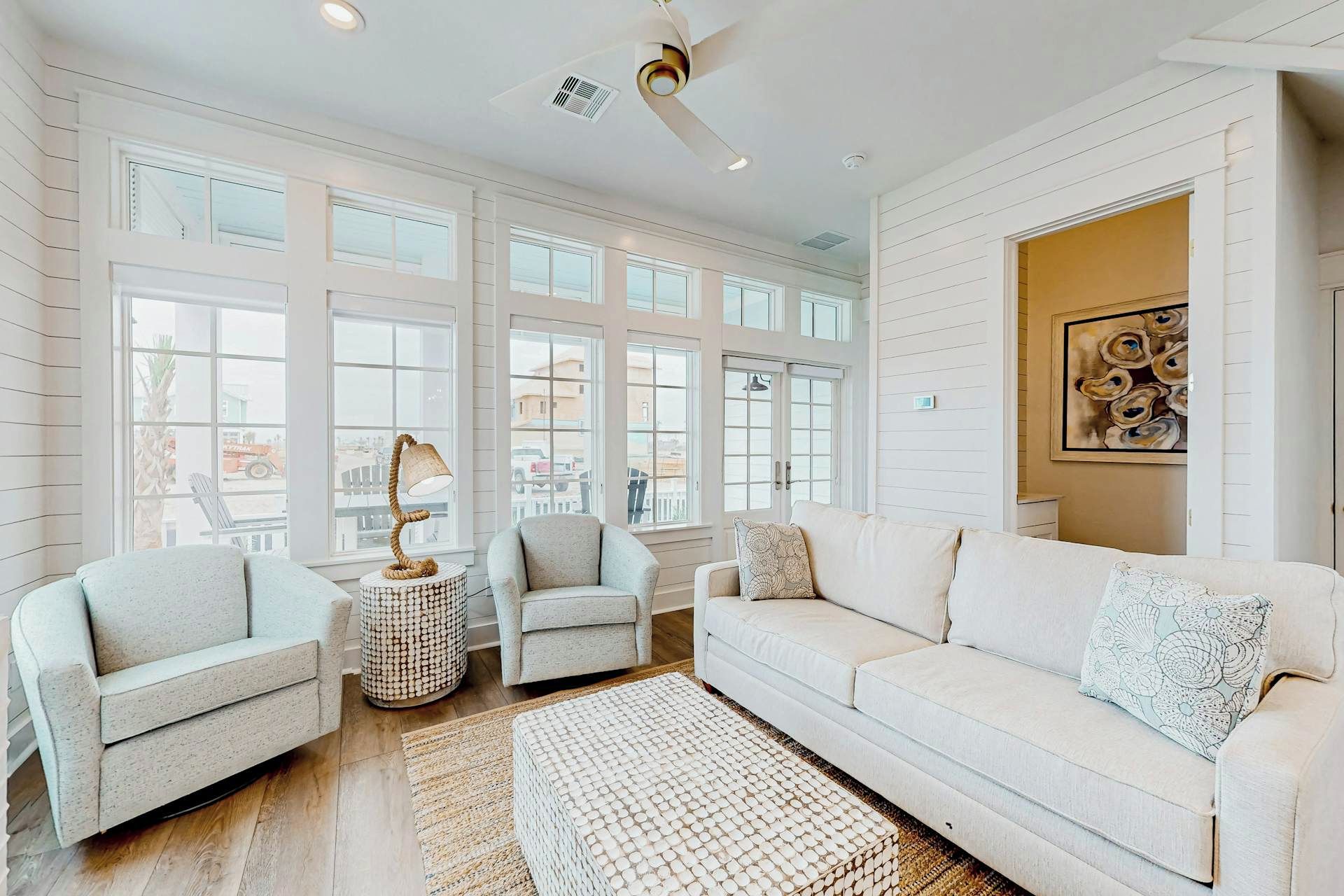 Une pièce spacieuse avec une grande fenêtre, un ventilateur de plafond et un canapé.