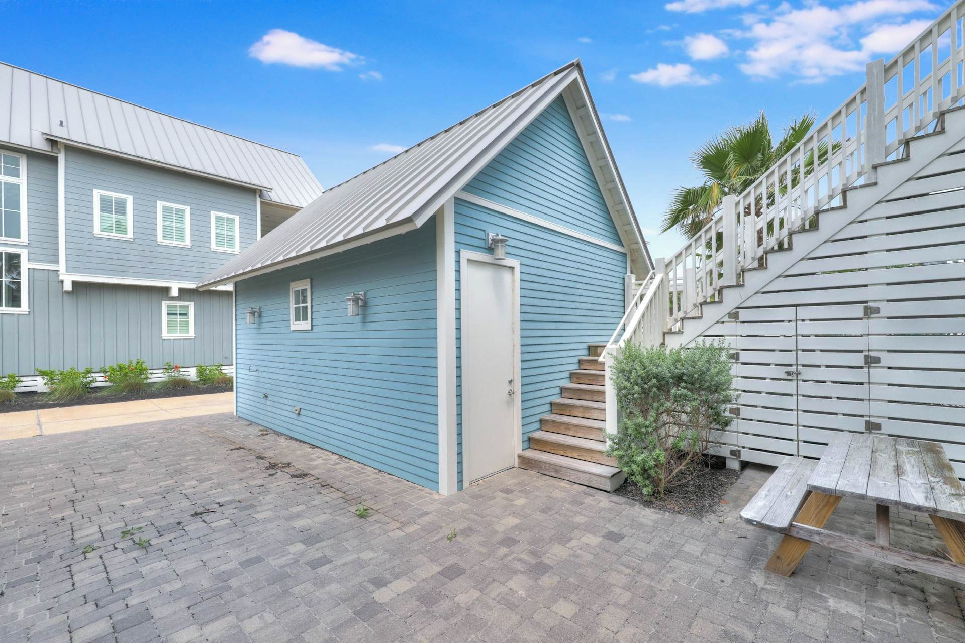 Ein Wohnhaus mit einem blauen Haus, einer Holztreppe und einem Picknicktisch.