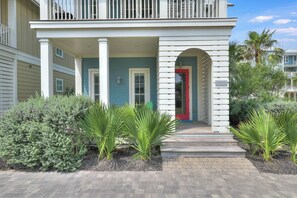 A two-story building with a covered porch, a red door, and a sign reading 'The Seaside Trip.' - The Sand Trap | Pet Friendly | Steps to Beach (Port Aransas)