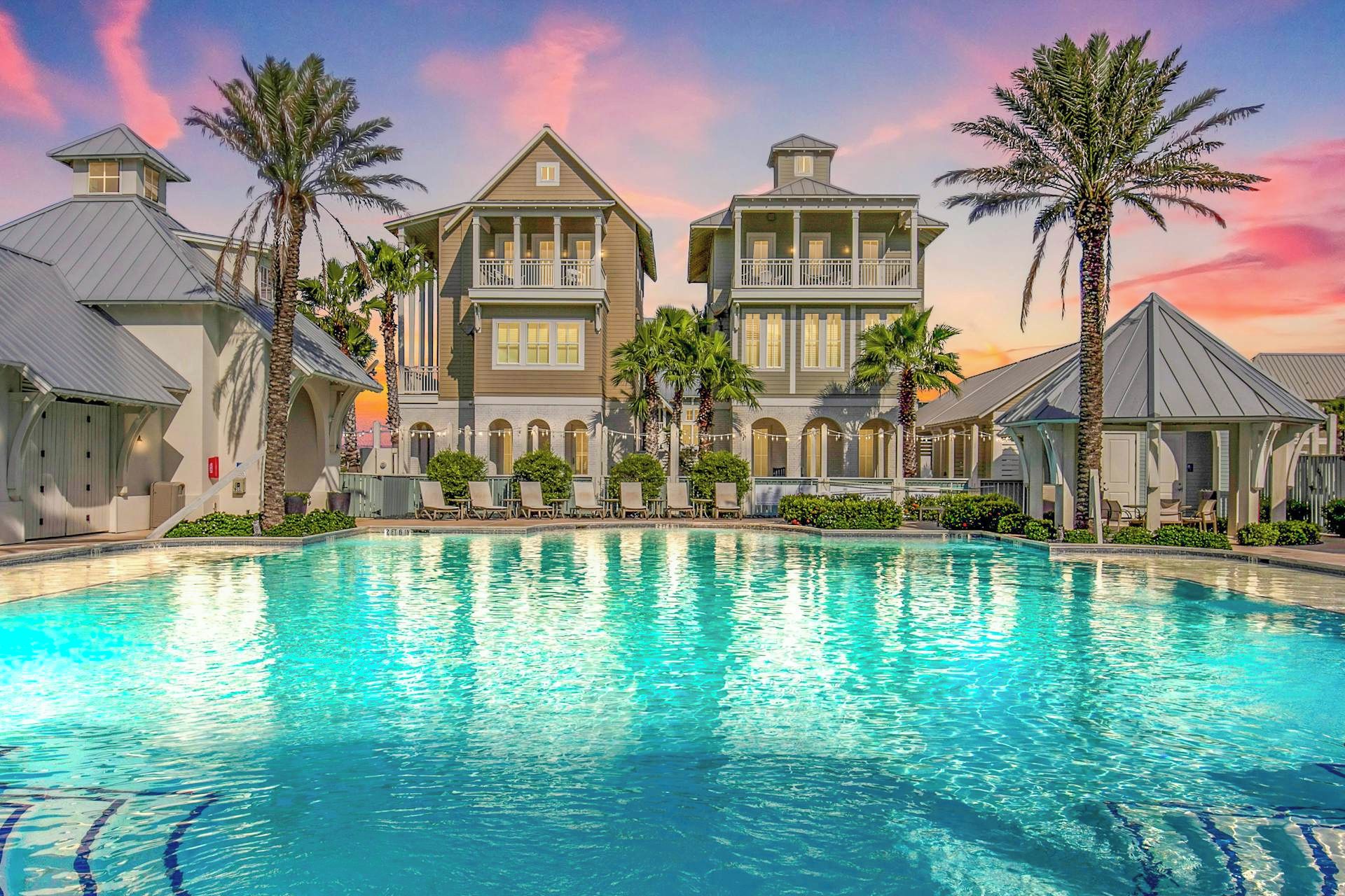 A large resort with a swimming pool, multiple buildings, and palm trees.