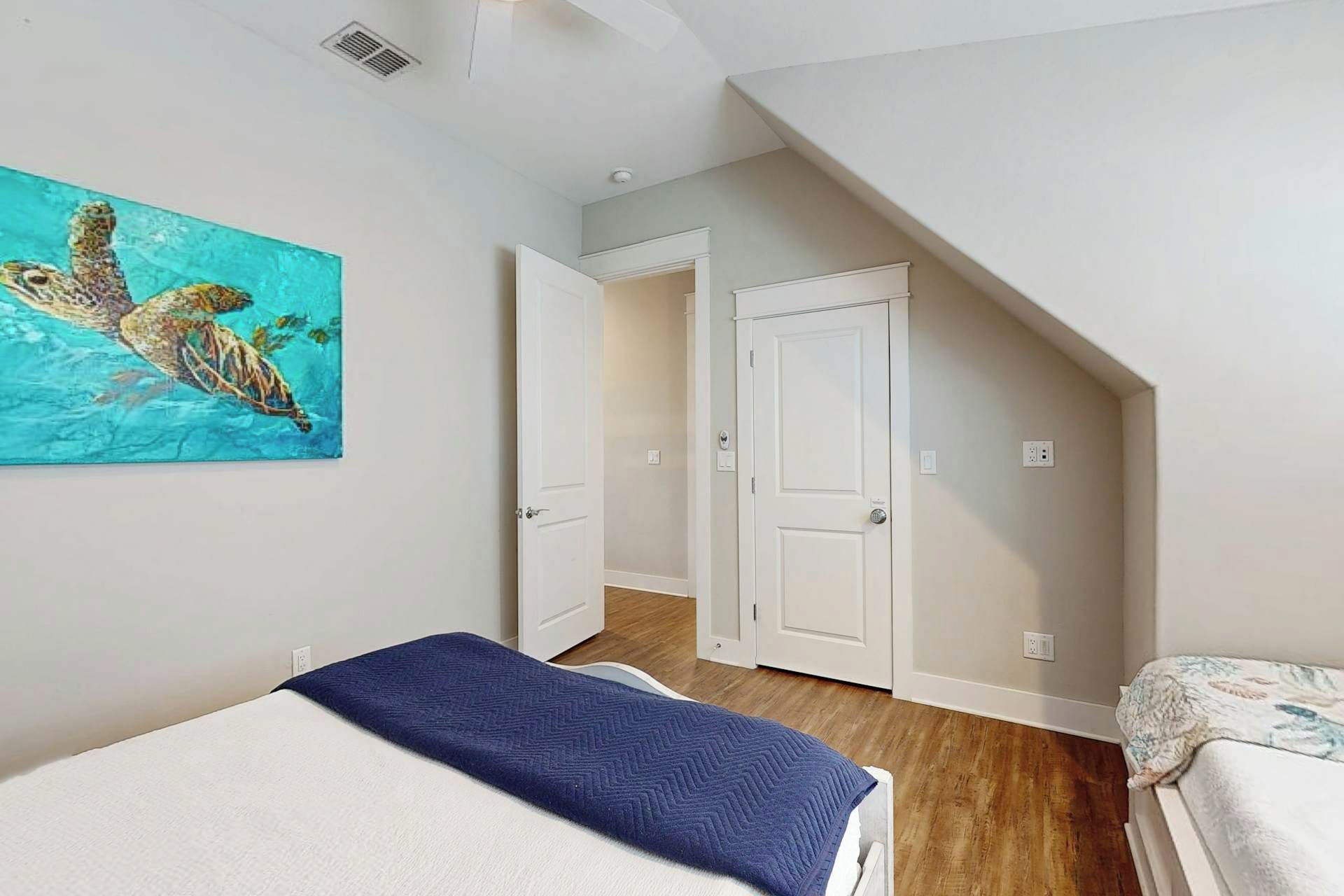Ein Schlafzimmer mit einem Bett, einem Gemälde und einer Tür zu einem anderen Raum.