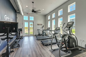 A gym with treadmills, elliptical machines, and a stationary bike. - Third Coast Charm | Pool Steps Away | Balconies (Port Aransas)