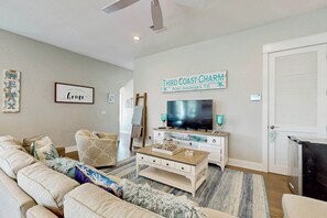 En stue med en sofa, et sofabord, et fjernsyn og et skilt der står 'Third Coast Charm Port Aransas, TX'.