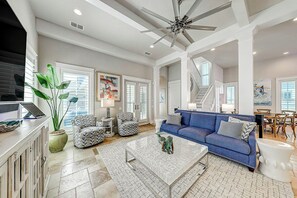 A spacious living room with a blue sofa, a coffee table, and a large plant. - Private Pool | Steps to Beach | Resort Amenities (Port Aransas)