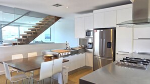 A modern kitchen with a central island, stainless steel appliances, and a staircase leading to an upper level. - Beach & Bubbles, Moonta Bay (Moonta Bay)