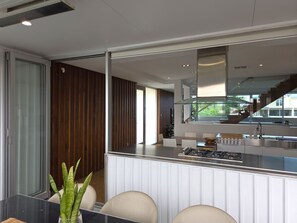 Une cuisine moderne dotée d’un îlot central, d’appareils électroménagers en acier inoxydable et offrant une vue sur l’extérieur.