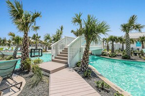 Ein Poolbereich mit Holzterrasse, Palmen und einer Treppe zu einem Gebäude.