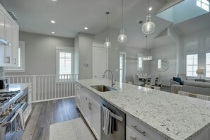A modern kitchen with granite countertops, stainless steel appliances, and pendant lighting. - Green Turtle Cottage | Steps to Beach and Resort (Port Aransas)