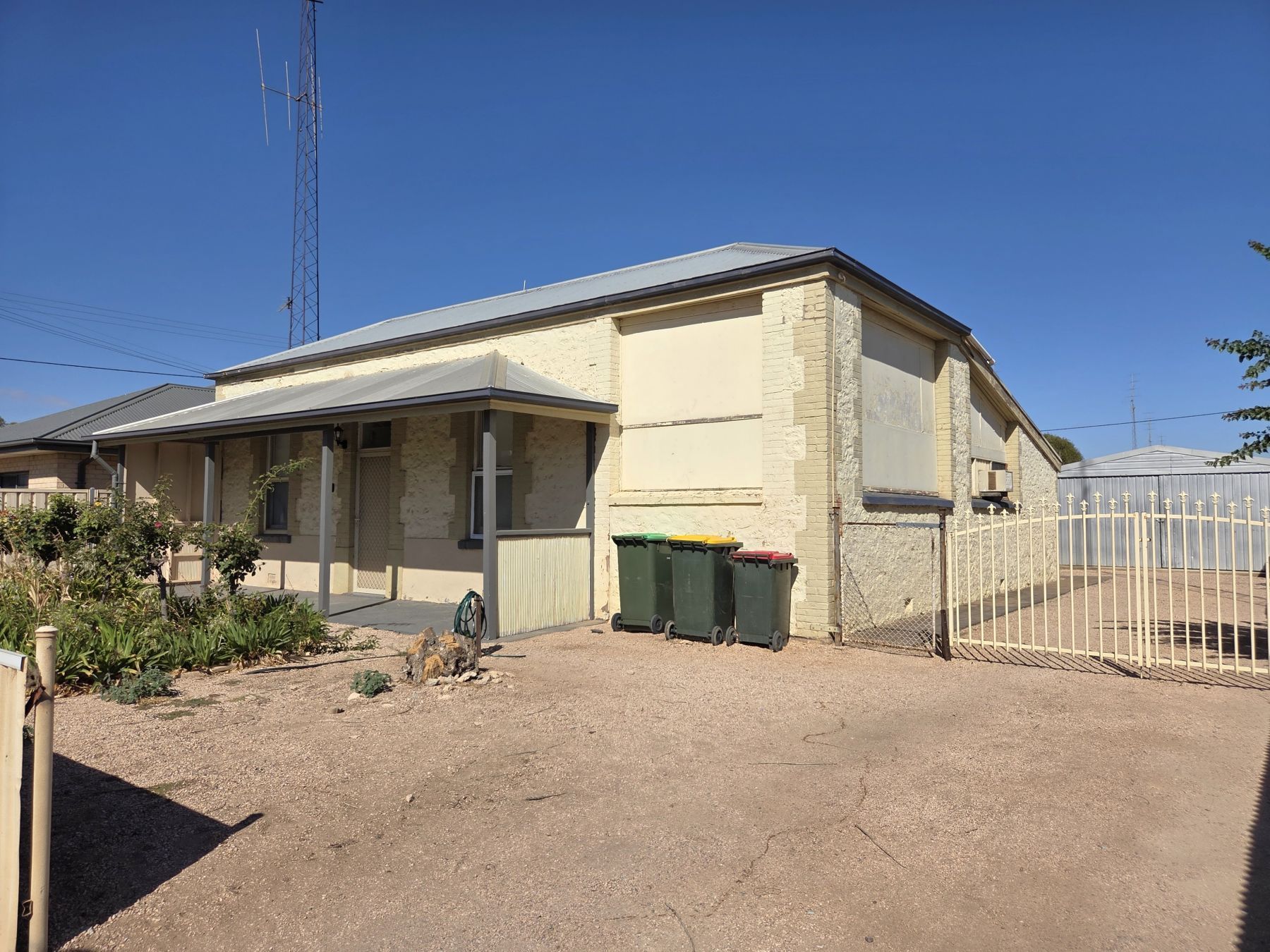 A single-story building with a flat roof, a covered porch, and a fenced yard.