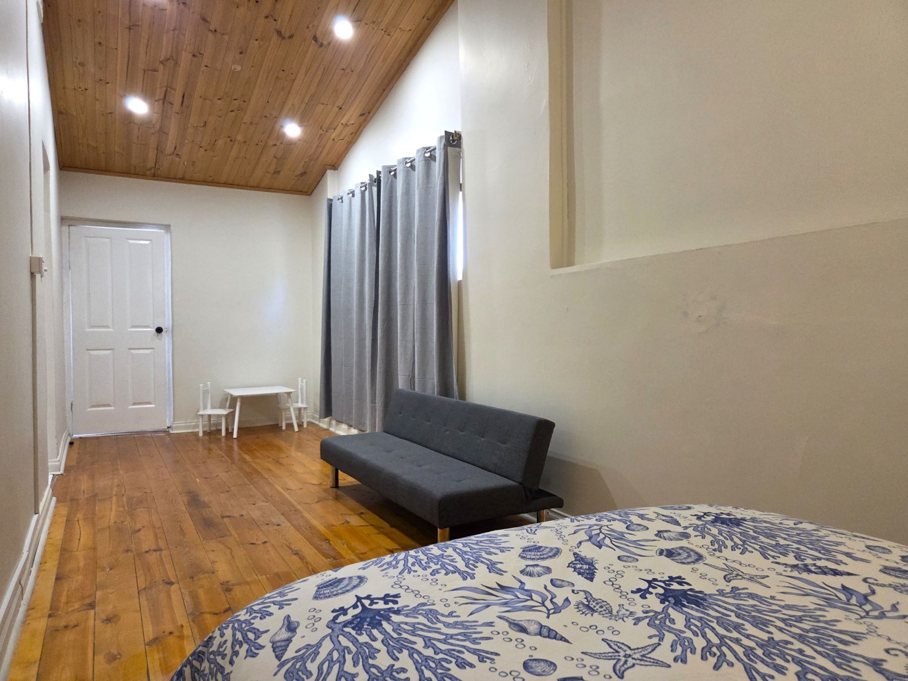 Un dormitorio con cama, sofá, una mesita y una silla.