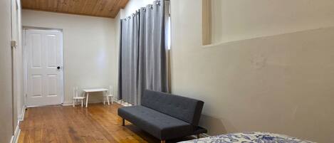 Un dormitorio con cama, sofá, una mesita y una silla.