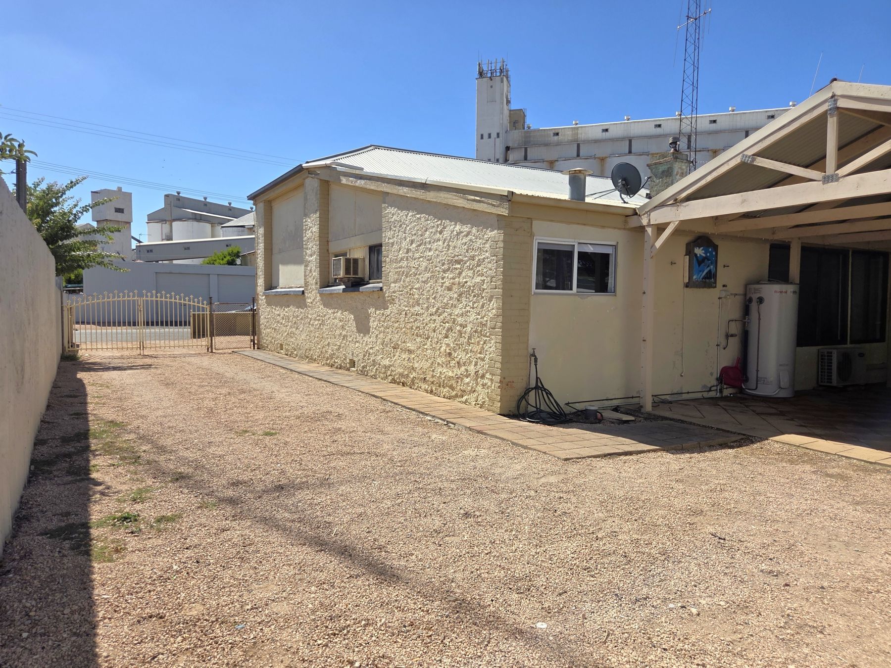 A residential building with a gravel driveway, a fenced area, and a water tank.