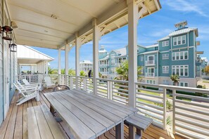A covered outdoor area with wooden benches and a view of multi-story buildings. - Silverado Waves | Steps to Beach |Resort Amenities (Port Aransas)