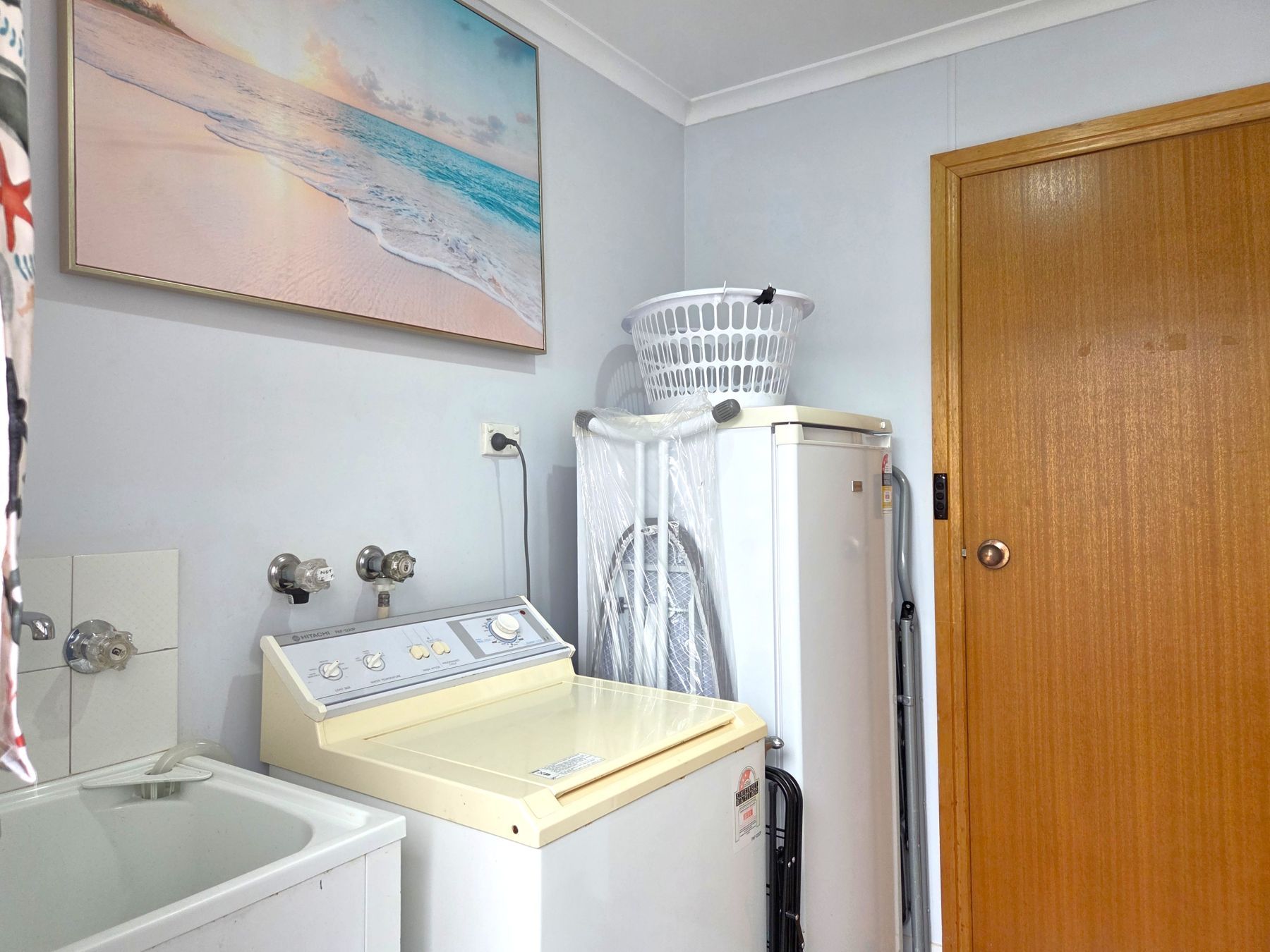 A bathroom with a washing machine, a heater, and a wooden door.