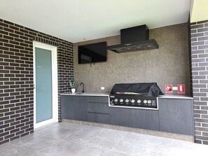 A modern kitchen with a built-in grill, a window, and a door. - Belless at Moonta Bay, Moonta Bay (Moonta Bay)