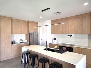 A modern kitchen with wooden cabinets, a marble countertop, a stainless steel refrigerator, a coffee machine, and a dishwasher. - Belless at Moonta Bay, Moonta Bay (Moonta Bay)