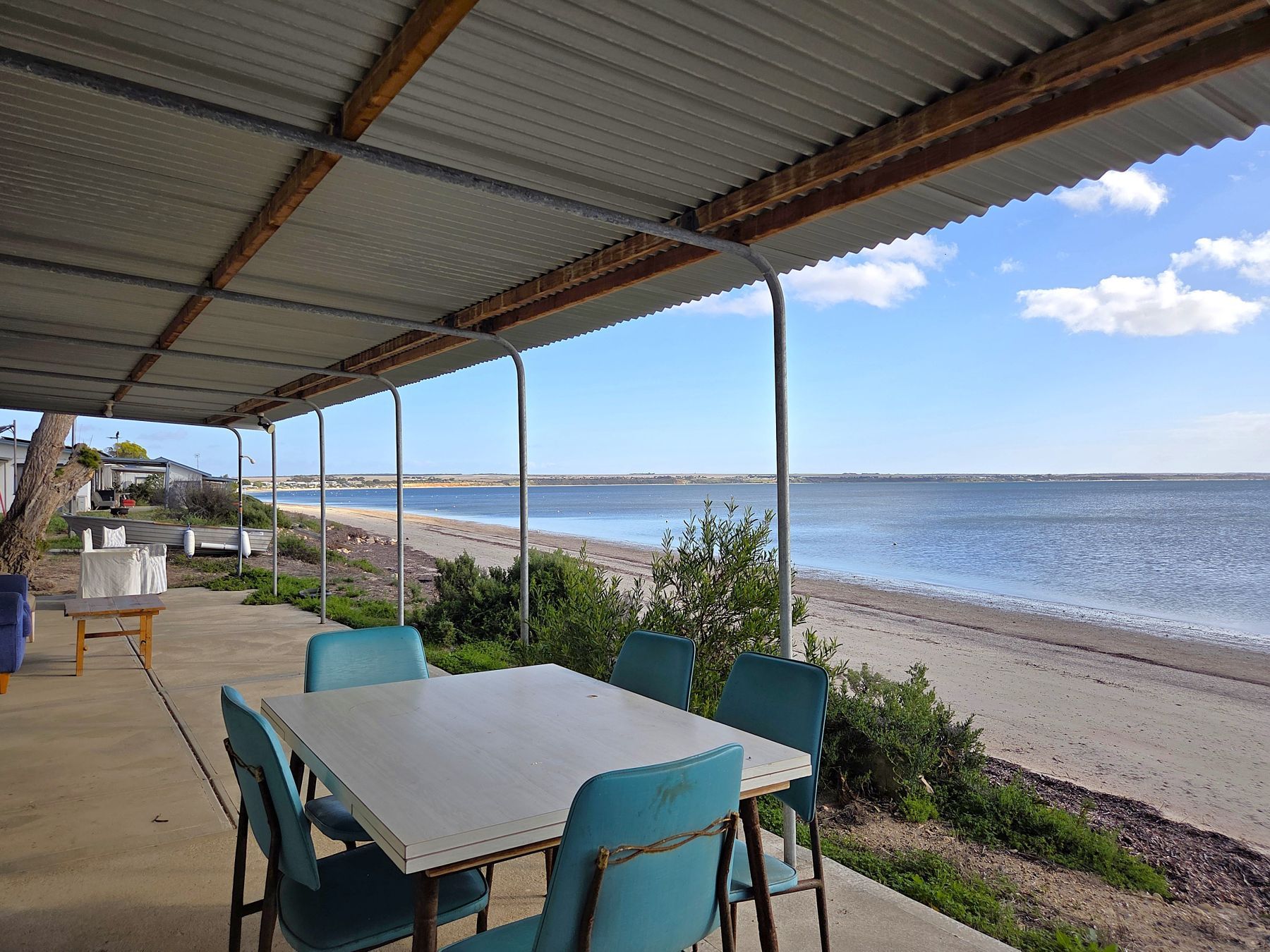 A covered outdoor seating area with a view of the beach and ocean.