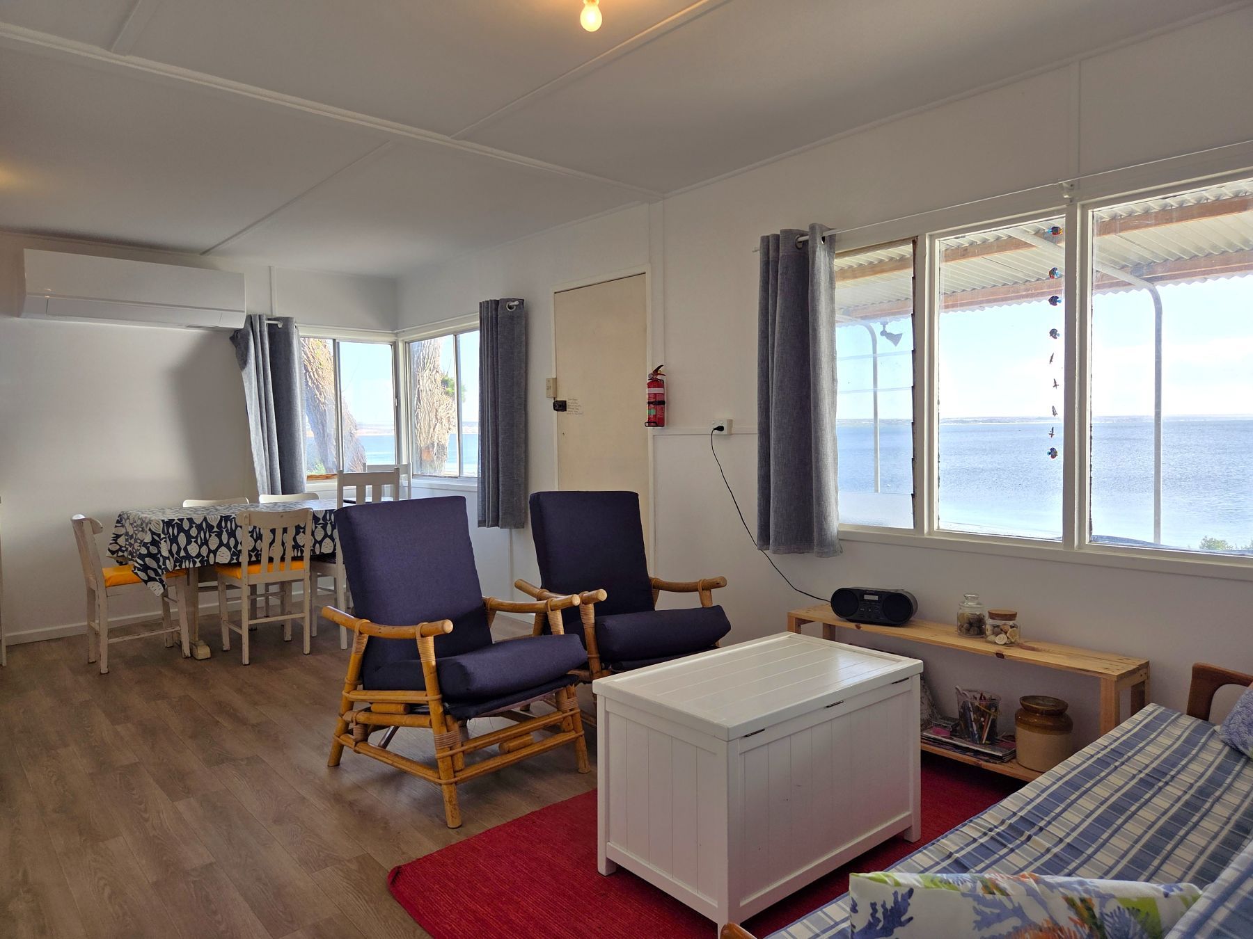 Ein Zimmer mit einem Bett, einem Sessel, einem Tisch und Meerblick.