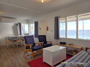 Une chambre avec un lit, une chaise, une table et une vue sur la mer.