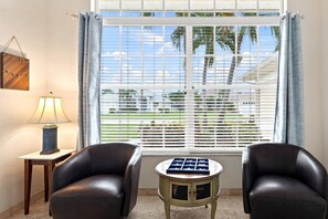 A room with two leather chairs, a small table with a chessboard, a lamp, and a window with blinds. - Cape Coral Waterfront Escape | Close to Shopping & Dining | Heated Pool, Private Dock & Gulf Access (Cape Coral)
