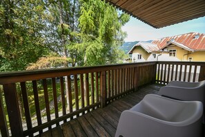 A wooden deck with a railing, overlooking a residential area with houses and trees. - Zell City Exclusive Lodges: Top 3, Balcony (Zell am See)