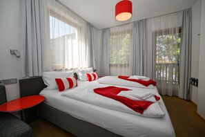 A modern hotel room with a large bed, a small table, and a view of the outdoors. - Zell City Exclusive Lodges: Top 3, Balcony (Zell am See)