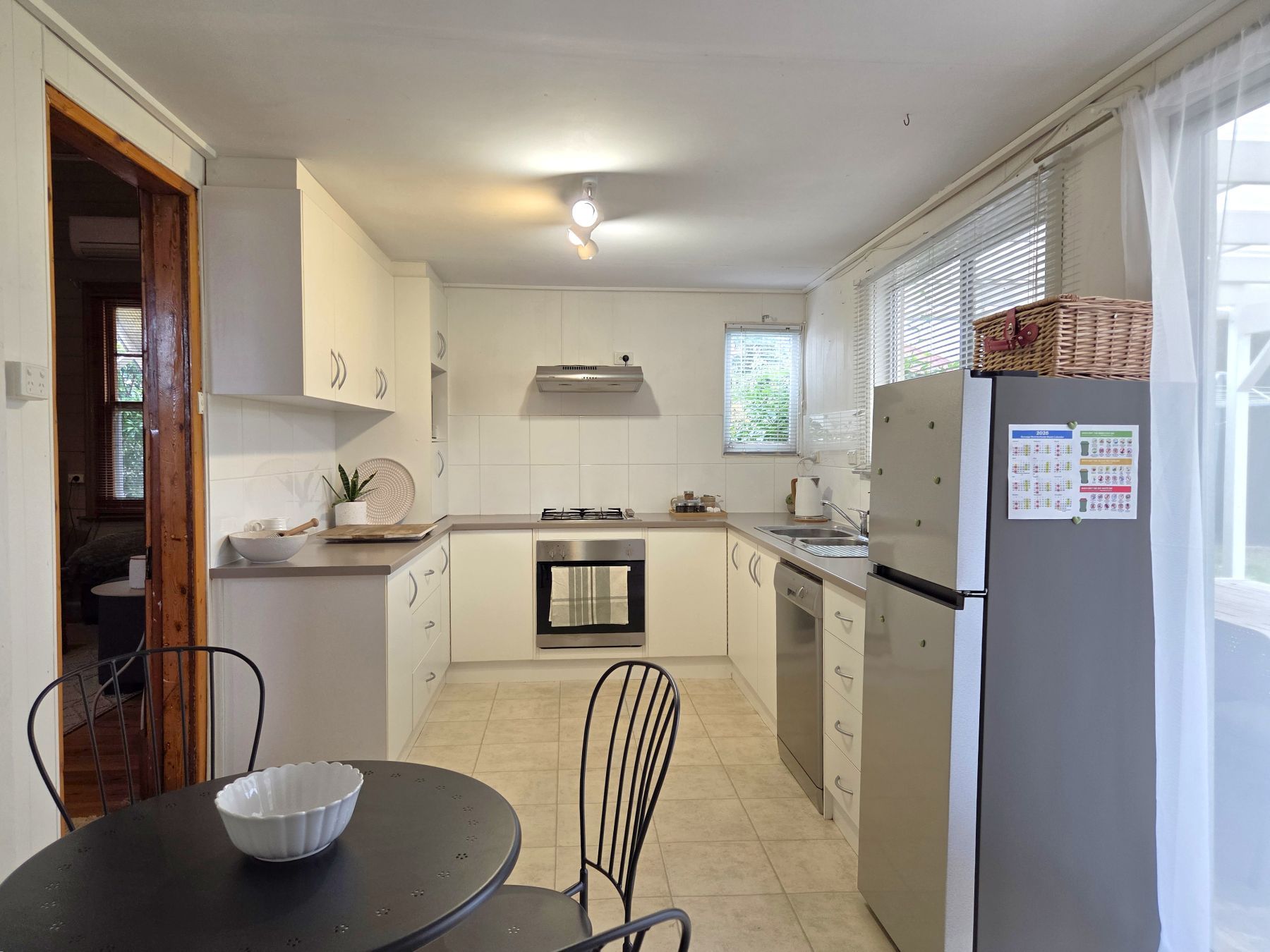 A compact kitchen with white cabinets, a gas stove, a built-in oven, and a refrigerator.