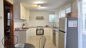 A compact kitchen with white cabinets, a gas stove, a built-in oven, and a refrigerator.