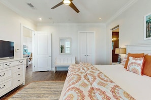 A bedroom with a bed, a television, a dresser, a ceiling fan, and a door leading to another room. - Pet-Friendly | Water Views | Steps to Beach (Port Aransas)