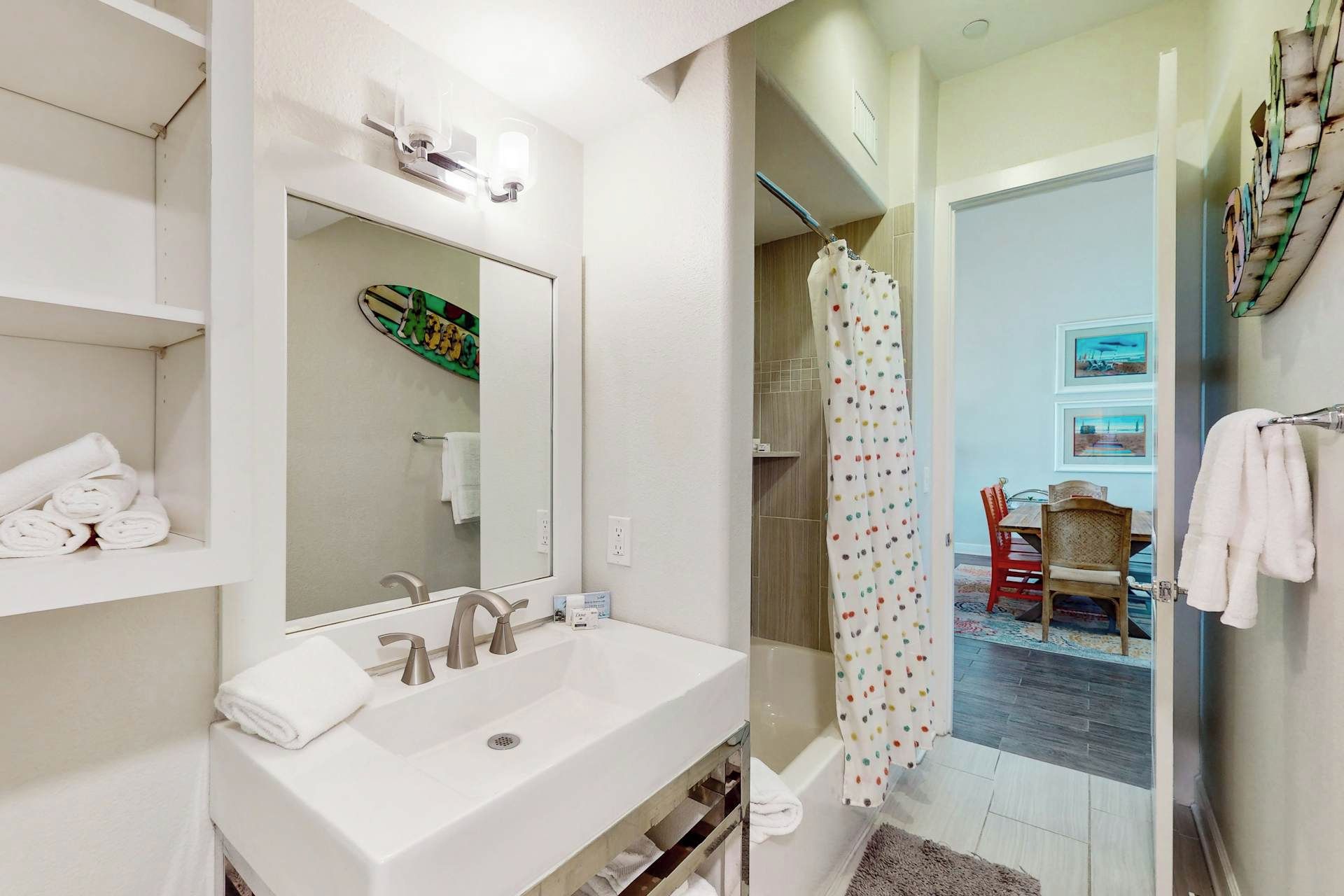 Une salle de bain avec un lavabo blanc, un miroir et un rideau de douche.