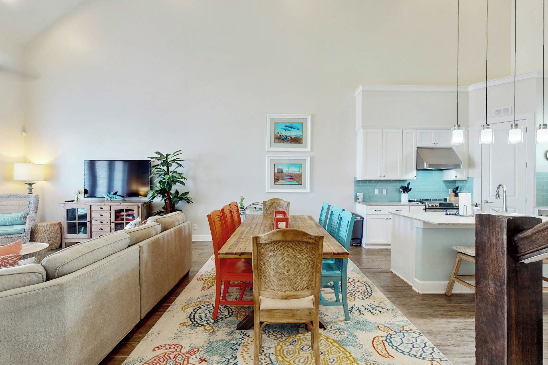 A modern living room with a sofa, a dining table with chairs, a TV, and artwork on the wall.