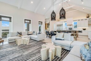A spacious living area with a large sofa set, a dining table, and a kitchen in the background. - Palmilla's Sunset | Pet Friendly | Steps to Beach (Port Aransas)
