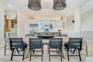 A modern kitchen with a central island, white cabinetry, and black chairs. - Palmilla's Sunset | Pet Friendly | Steps to Beach (Port Aransas)