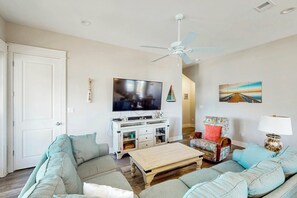 A living room with a flat-screen TV, a ceiling fan, a coffee table, and a sofa. - Perfect Pelican | Resort Amenities| Beach Access (Port Aransas)