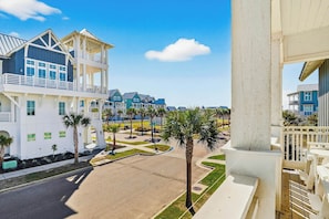 A residential area with modern houses, a clear sky, and a well-maintained lawn with palm trees. - Pines To Palms | Steps to Beach | Resort Amenities (Port Aransas)